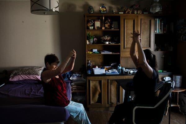 Ms. McVean raises her hands above her shoulders during an exercise with her therapist.